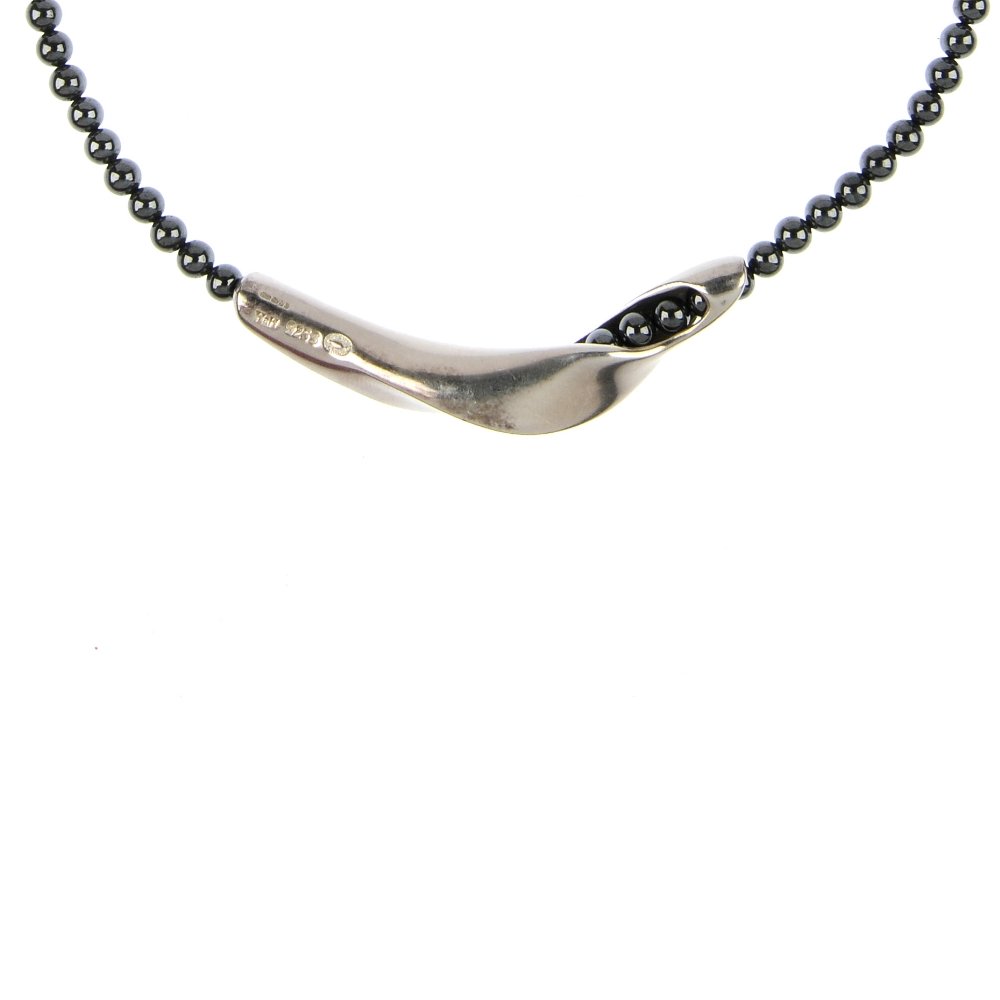 GEORG JENSEN - a silver haematite bead necklace: GEORG JENSEN - a silver hematite bead necklace, the curved sculpted panel, to the spherical hematite beads. Signed Georg Jensen. Hallmarks for London, 2000. Length 38.6cms. Weight 32.5gms.