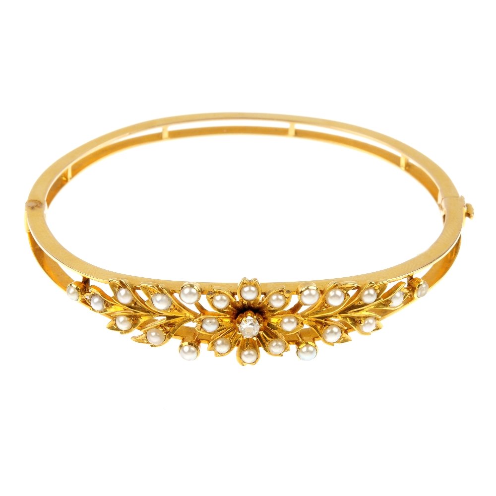 An early 20th century 15ct gold diamond and split pearl: An early 20th century 15ct gold diamond and split pearl hinged bangle. The front designed as an old-cut diamond and split pearl flower, to the split pearl foliate sides and openwork bangle. Inner diam