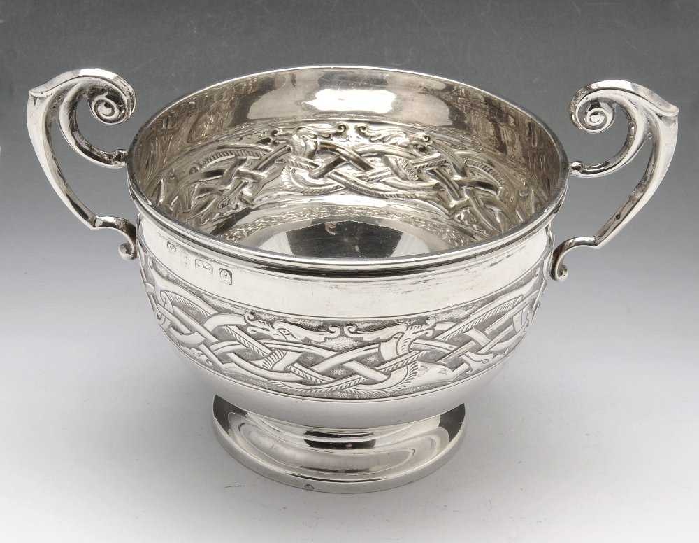 An Edwardian silver bowl.: An Edwardian silver bowl with Celtic embossed band to the twin high arch scrolling handles and circular footed base. Hallmarked Williams (Birmingham) Ltd, 1904. Height including handle 3 1/2 inches (9