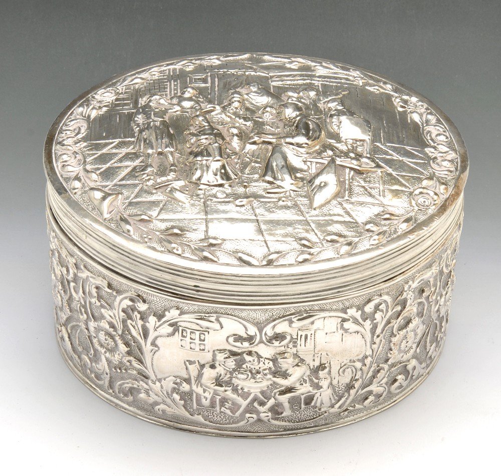 Two Dutch silver boxes.: A Dutch silver box of oval form and hinged lid, embossed with figurative scenes with floral scroll borders, height measuring 2 3/4 inches (7 cm). Together with a smaller Dutch hinged silver box of sim