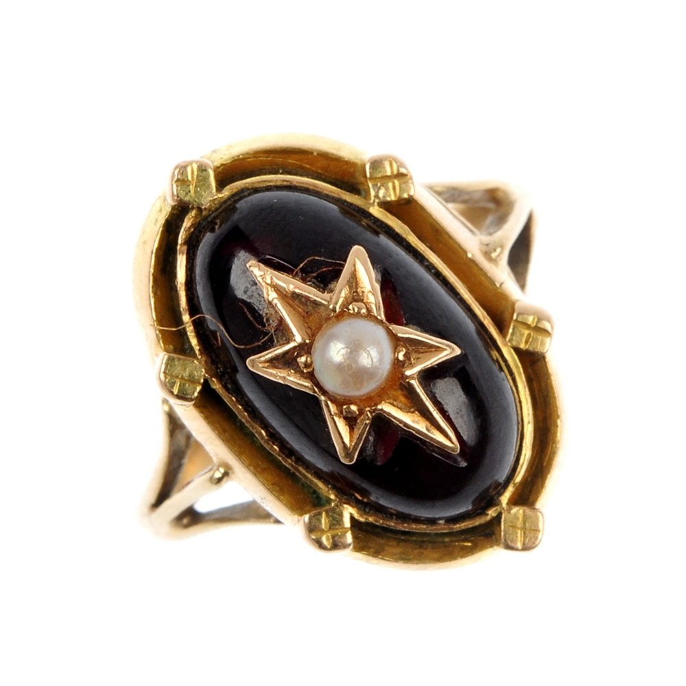 A garnet and split pearl ring.: A garnet and split pearl ring. The oval garnet cabochon, with split pearl star centre, to the double surround with flattened bead detail and bifurcated shoulders. Weight 6.1gms.