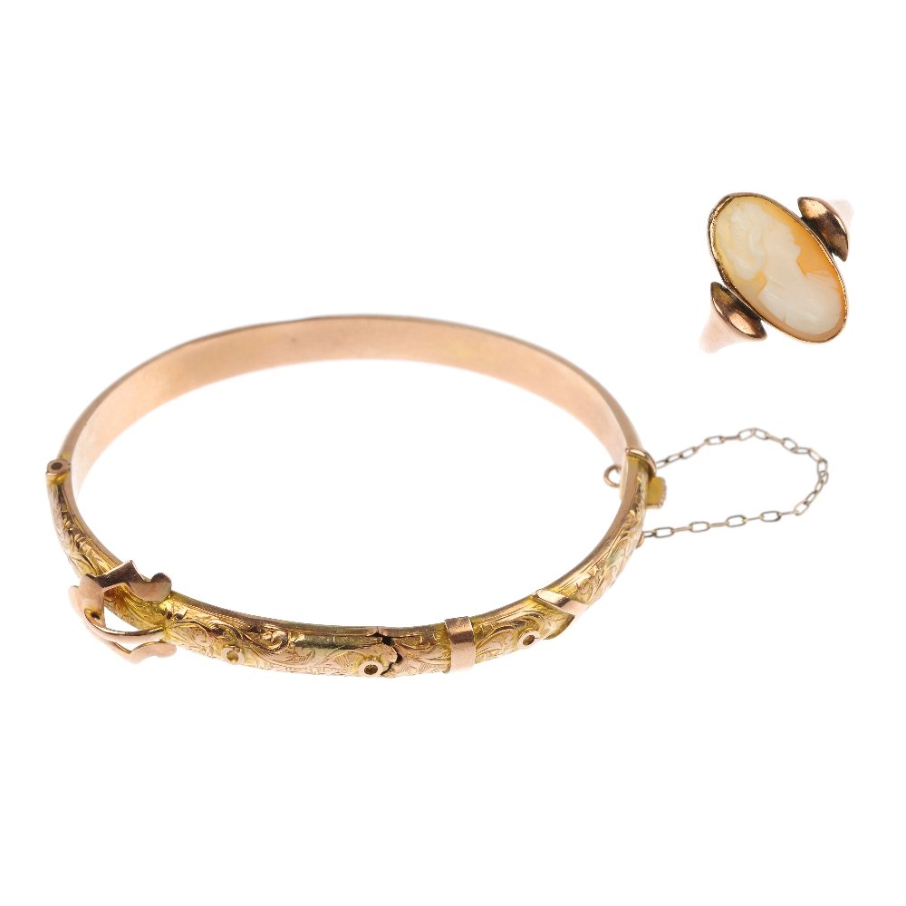An early 20th century 9ct gold hinged bangle and a: An early 20th century 9ct gold bangle and a cameo ring. The front designed as scrolling buckle to the plain half-bangle, together with an oval-shape shell cameo ring depicting a lady in profile. Bangl