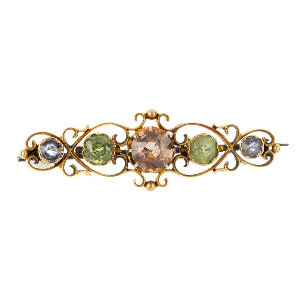 A late 19th century gold gem-set brooch.: A late 19th century gold gem-set brooch. Of openwork design, the circular-shape brown zircon, to the graduated circular-shape peridot and sapphire sides, within a scrolling surround. Length 4.3cms. We