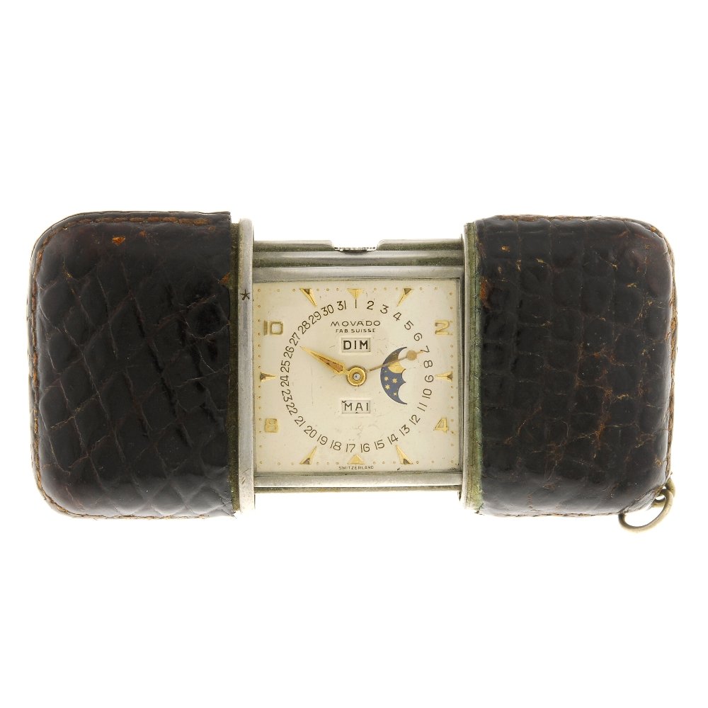 A Movado travel clock in case.: A stainless steel manual wind travel clock signed Movado, the brown caiman skin covered case sliding open to reveal a silvered dial with hourly applied Arabic numerals interspaced with markers, moon p