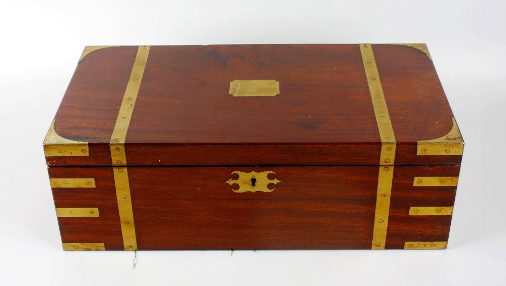 A 19th century brass-bound mahogany 'Campaign' style: A 19th century brass-bound mahogany 'Campaign' style writing box or lap desk, the hinged cover with brass corners, straps and central cartouche, enclosing a gilt tooled blue hide skiver slope, pen tra