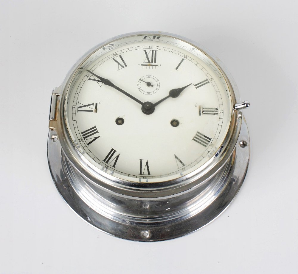 A metal cased ships bulk head style clock: A metal cased ships bulk head style clock, the circular drum shaped case with bevel edged glazed door, the painted white circular dial with black numerals and hands, marked 'Made in Germany', dial 6.5