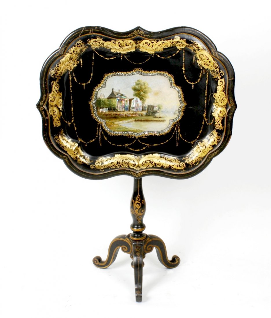 A 19th century black lacquered and papier mache snap: A 19th century black lacquered and papier mache snap top table, the rectangular tray top with scalloped edge, hand painted to the centre with a panel depicting buildings upon the bank of a river inset