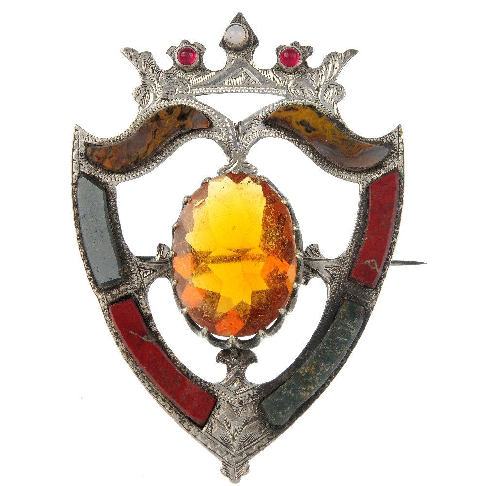 A late Victorian Scottish brooch.: A late Victorian silver Scottish brooch, the engraved silver shield-shape outline with central oval orange paste, set with jasper, bloodstone and agate and paste circular cabochons to the crown. Lengt