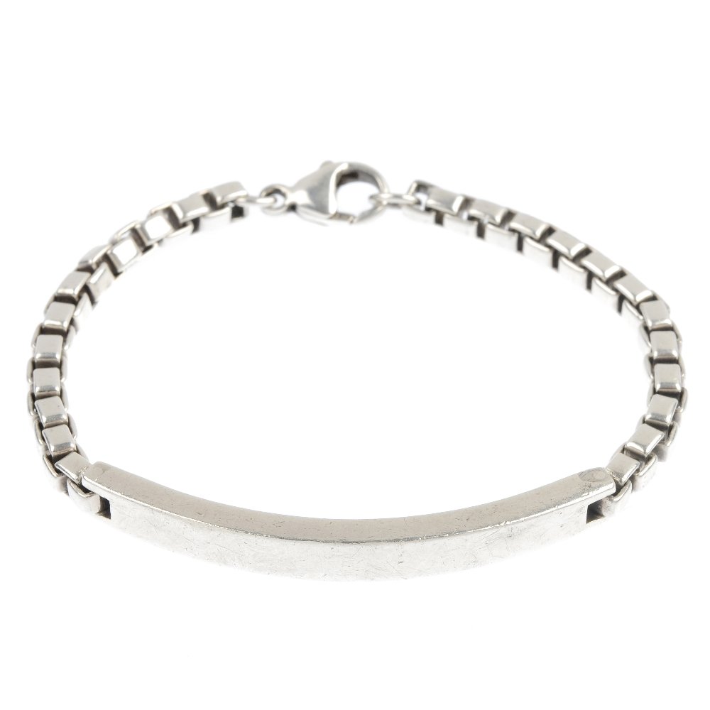 TIFFANY & CO. - a heart pendant and a bracelet.: TIFFANY & CO. - a pendant and bracelet, the silver heart pendant by Elsa Peretti, together with a box-link chain identity bracelet. Pendant signed Elsa Peretti, Tiffany & Co. Bracelet signed Tiffany &