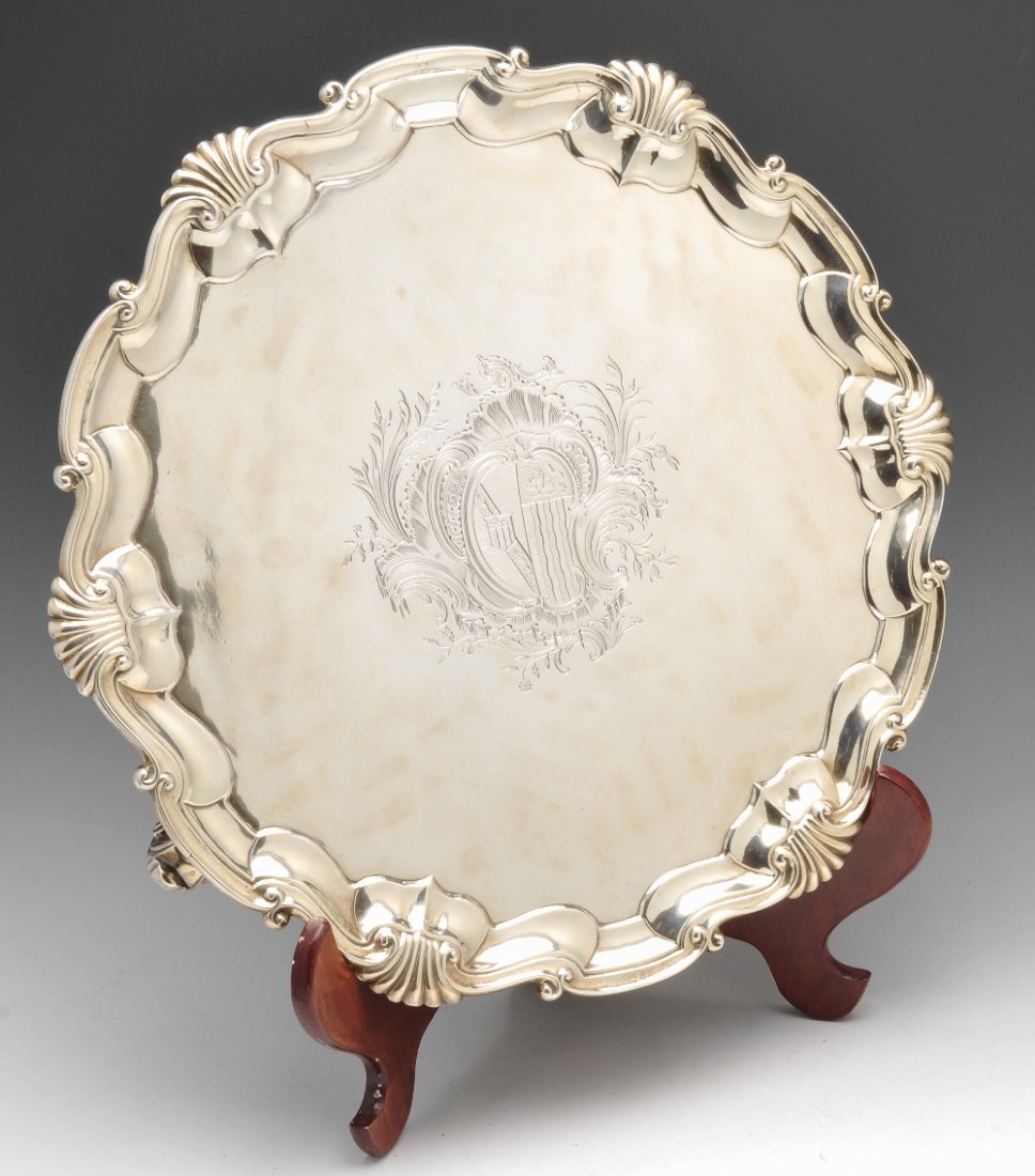 A George II silver salver, Hugh Mills London 1748.: A George II silver salver, the circular form with central engraved armorial to the shaped raised edge with scroll and shell rim and raised above three scroll and ball feet. Hallmarked Hugh Mills, Lond
