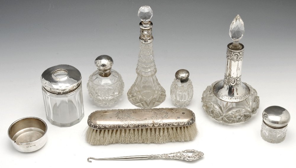 A selection of early 20th century silver mounted vanity: An early twentieth century selection of silver mounted vanity jars and dressing table items, to include two tapered glass scent bottles, a cylindrical glass bottle, three jars, a brush, button hook an