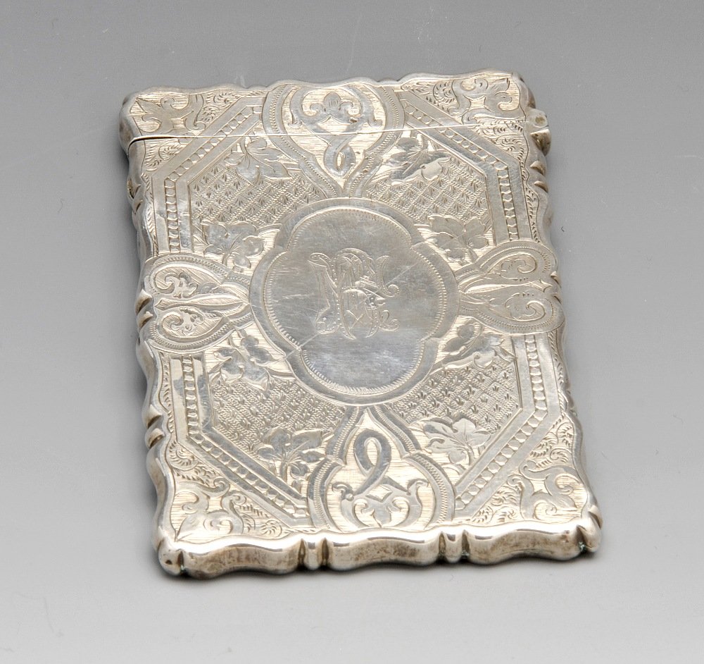 A Victorian silver card case.: A Victorian silver card case of oblong form, with scroll edge and a hinged lid, with bright cut engraved octagonal panel containing a large quatrefoil monogrammed cartouche, the reverse containing a s