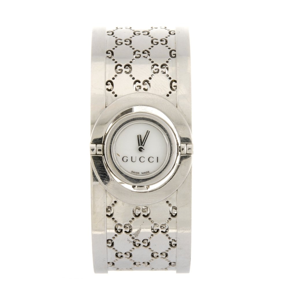 A stainless steel quartz lady's Gucci Twirl bangle: GUCCI - a stainless steel quartz lady's Twirl bangle watch, the white dial set within a round rotating case, fitted to a steel trellis pattern bangle with clasp. Bangle width 22mm.