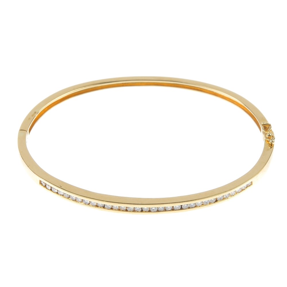 An 18ct gold diamond bangle.: * An 18ct gold diamond bangle. Designed as a brilliant-cut diamond line, to the plain half bangle. Estimated total diamond weight 0.60ct. Import marks for London. Inner diameter 5.9cms. Weight 12gms.