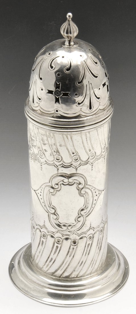 A late Victorian silver caster.: A late Victorian silver caster, raised on a flared and stepped foot rising to the cylindrical body flanked by oblique fluting, central vacant cartouche and domed pierced detachable cover. Hallmarked M