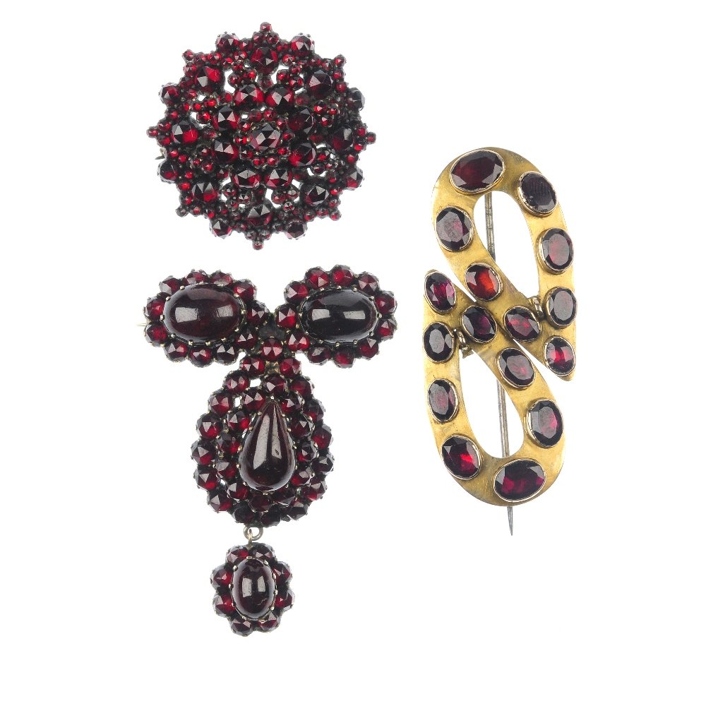 Three late 19th century garnet and paste brooches.: Three late 19th century garnet and paste brooches, to include a vari-shape garnet and red paste trefoil panel brooch suspending a similarly set drop, a cluster brooch, together with a graduated oval-s