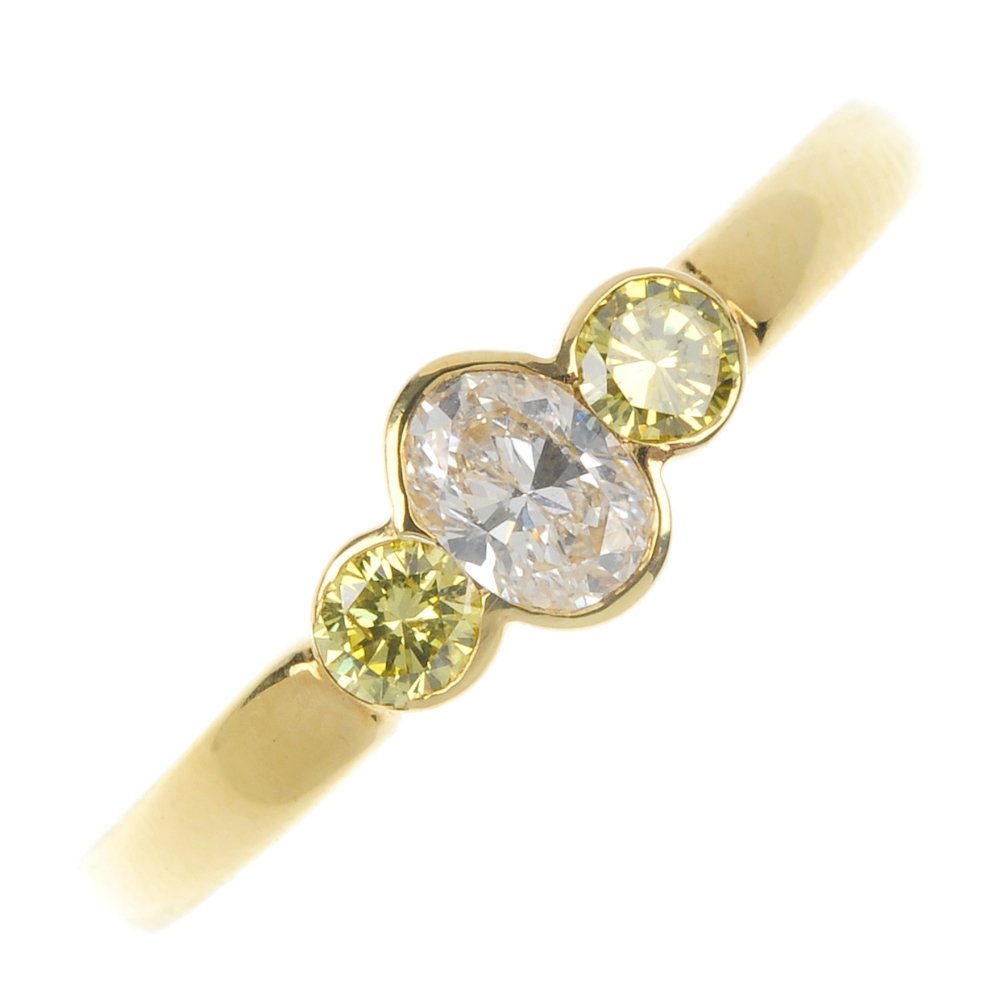 An 18ct gold colour-treated 'yellow' diamond and: An 18ct gold colour-treated diamond and diamond ring. The oval-shape diamond, with brilliant-cut colour-treated yellow diamond sides, to the plain band. Principal diamond estimated weight 0.25ct, I-J 
