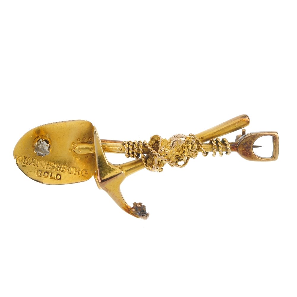 A late 19th century gold diamond Digger's brooch.: A late 19th century gold diamond Digger's brooch. Designed as a pick and shovel, with nugget and rope accent, the shovel with uncut diamond detail and stamped "Johannesburg gold". Length 5.5cms. Weigh