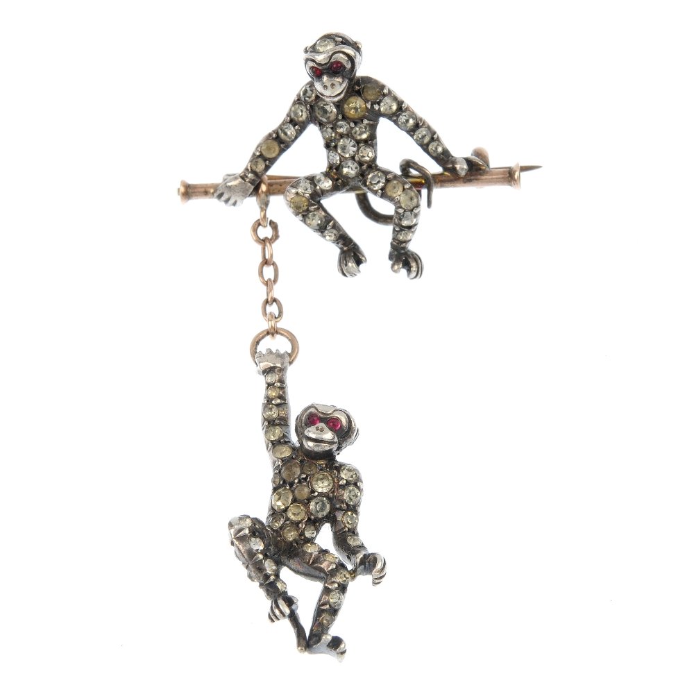 An early 20th century silver and gold paste monkey: An early 20th century silver and gold paste monkey brooch, designed as a colourless paste monkey sitting atop a bar, suspending a similarly-set monkey on a chain. Length 6.2cms. Weight 9gms.