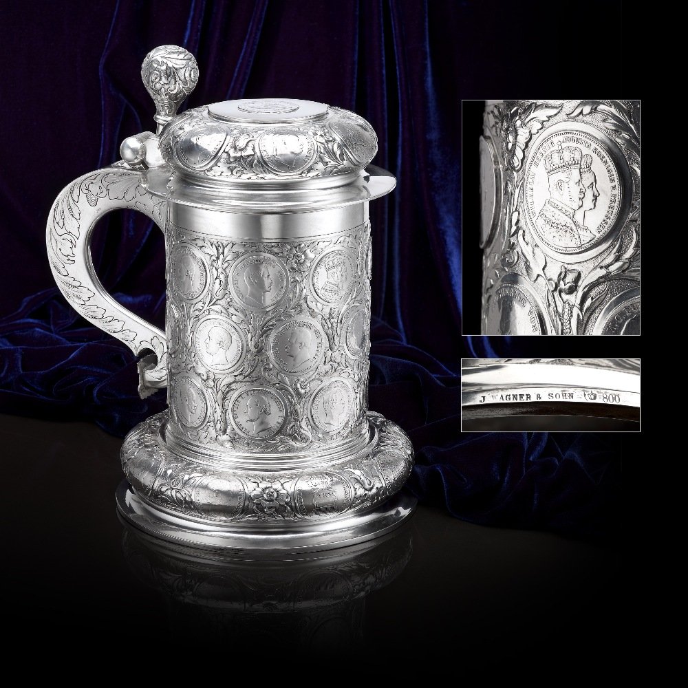 A large German tankard inset with coins by J Wagner &: A large German tankard by J Wagner & Sohn, the cylindrical body inset with twenty four coins, with a further nine coins to the spreading bulbous base and eight to the hinged lid including one inset to