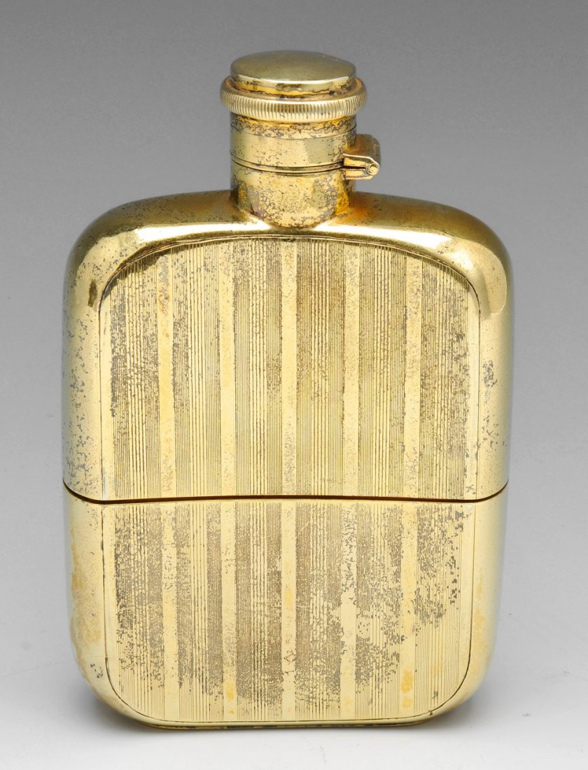 A 1920's silver-gilt hip flask with detachable cup.: A 1920's silver-gilt hip flask with detachable cup, of slightly curved oblong form with engine turned vertical line decoration throughout, a vacant circular panel to the top and the removable lower se