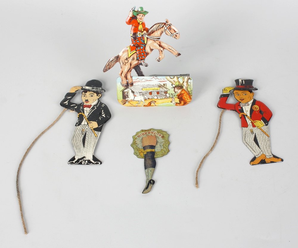 An early 20th century printed tinplate table top spinne: An early 20th century printed tinplate table top spinner amusingly modelled as a dancer's leg, detailed Bal-Tabarin Paris, plus an English tinplate novelty toy modelled as a Charlie Chaplin with 'doff