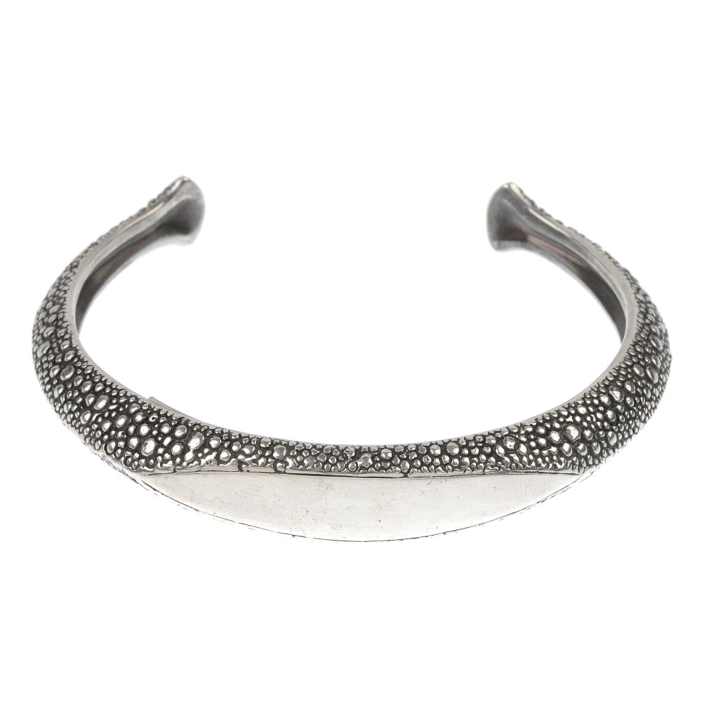 STEPHEN WEBSTER - a silver 'Reptile' bangle.: * STEPHEN WEBSTER - a silver 'Reptile' bangle, of torque design, the textured bangle, to the vacant marquise-shape panel. Maker's mark for Stephen Webster. Hallmarks for London, 2002. Inner diameter 6