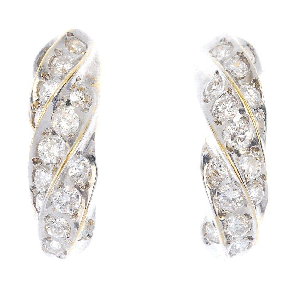 A pair of 18ct gold diamond earrings.: A pair of 18ct gold diamond earrings. Each designed as a curved bar with brilliant-cut diamond spiral line motif. Estimated total diamond weight 0.45ct. Import marks for London, 1983. Length 1.5cms. W