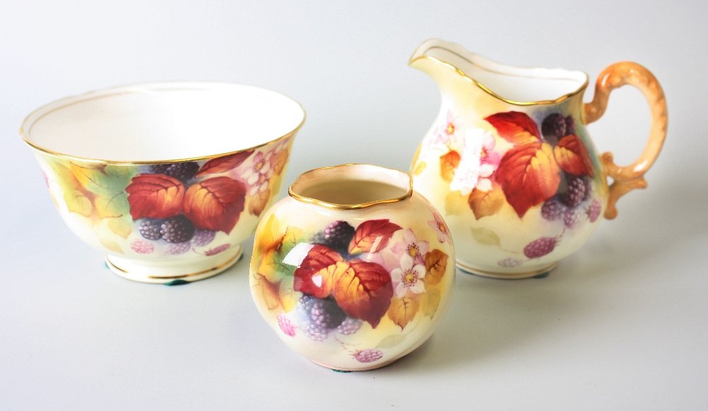 A Royal Worcester bone china vase of squat form: A Royal Worcester bone china vase of squat form, the plain ground with hand painted berries and leaves, signed K. Blake (Kitty), 2.75" (7cm) high, together with a similar cream jug and matching sucrie