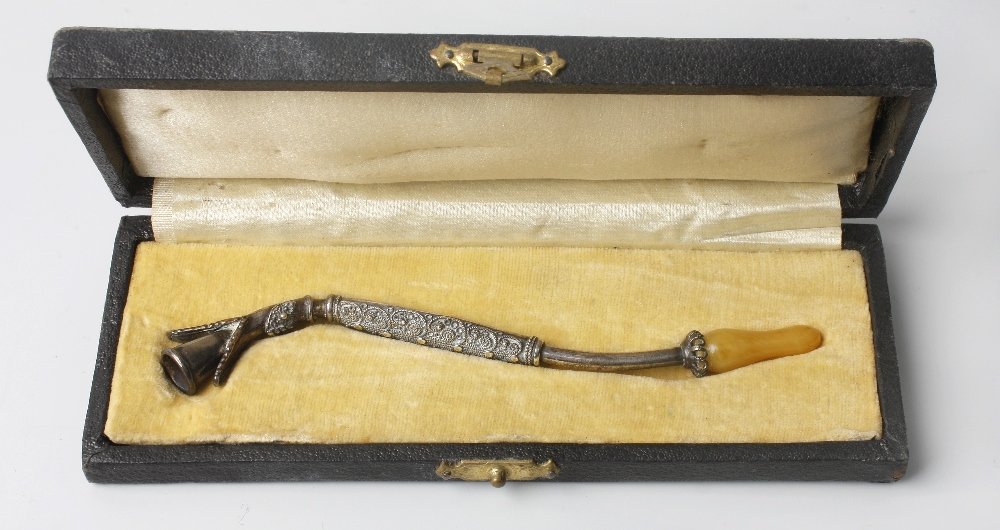 A Middle Eastern style pipe: A Middle Eastern style pipe, with base metal body of serpentine form with fluted end, decorated middle section and amber-effect mouthpiece, 5.25" (13.5cm) long, in fitted box.