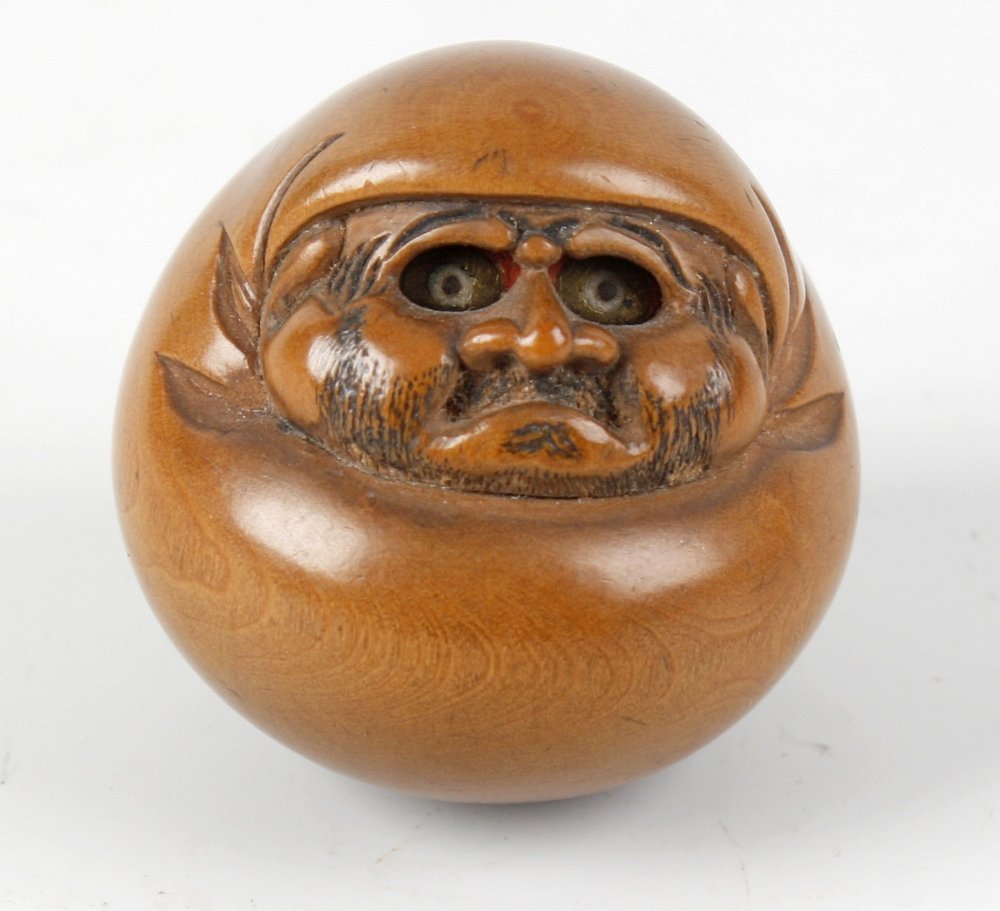 A Japanese Meiji period wooden netsuke: A Japanese Meiji period wooden netsuke, of round form, carved as a bearded man with inset eyes, signature to back, 1.25" (3.75cm) high.