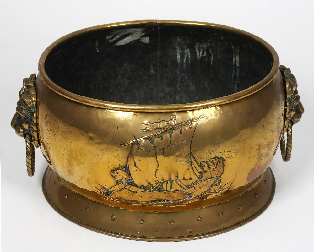 A 19th century Dutch brass log bin: A 19th century Dutch brass log bin, of bulging oval form with rolled rim over repousse decoration of a galleon between substantial cast lion mask and ring handles, with copper studded rear seam on con
