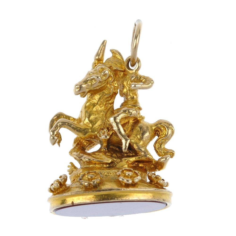 A hardstone novelty fob.: A hardstone novelty fob. The oval-shape carnelian panel, to the novelty pedestal, depicting Saint George and the Dragon. Length 3.6cms. Weight 21.6gms.