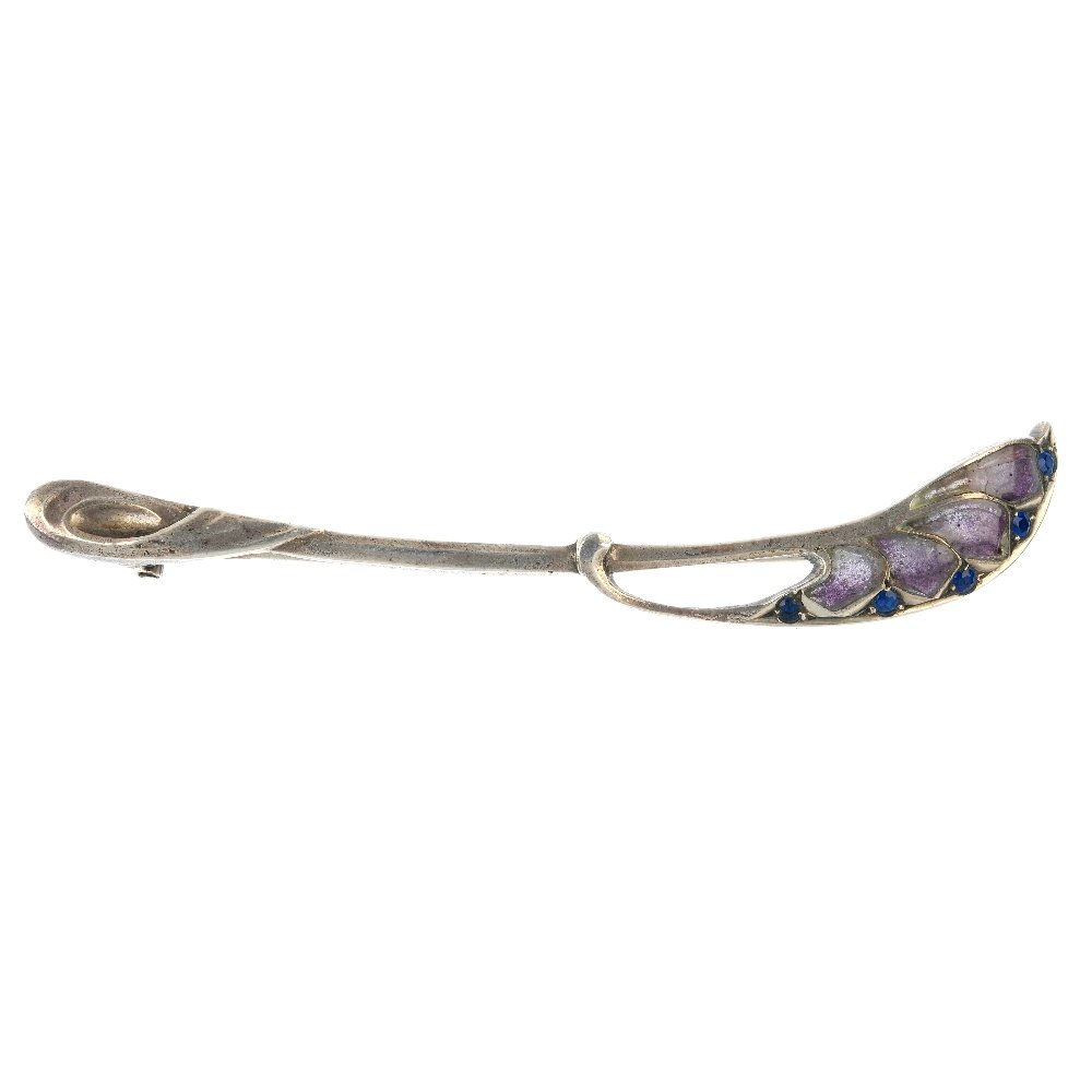 An early 20th century German Jugendstil plique-a-jour: An early 20th century German Jugendstil plique-a-jour enamel and paste brooch, the purple enamel and blue paste curved line, to the tapered bar and scrolling terminal. Length 7.6cms. Weight 6.5gms.