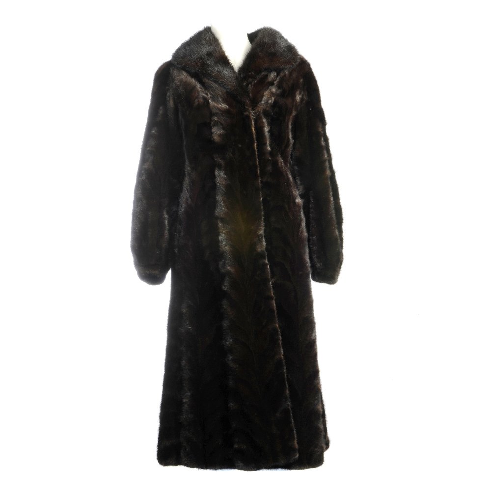 A full-length dark ranch mink pieced coat.: A full-length dark ranch mink pieced coat with full mink lapel collar, hook and eye clip fastenings, barrel sleeves, two outer pockets and a floral stitched motif to the bottom of the inner lining. Be
