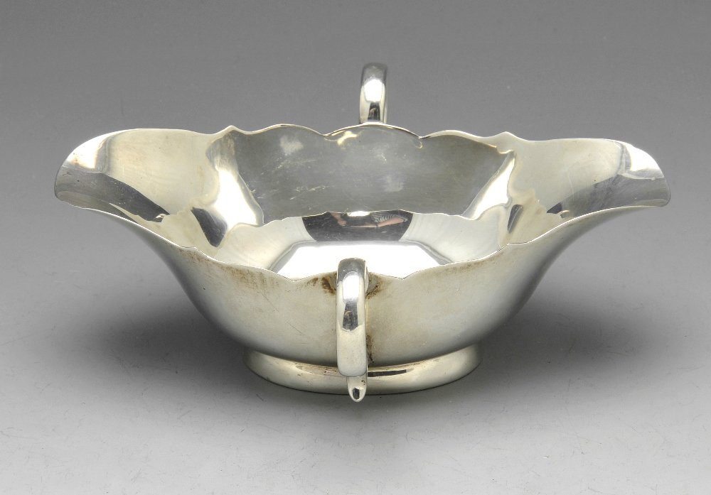 A turn of the century silver sauce boat, toast rack and: An Edwardian silver twin-handled sauce boat with dual lip, hallmarked Charles Stuart Harris, London 1901, maximum length measuring 5 1/4 inches (13 cm). Together with an early twentieth century silver