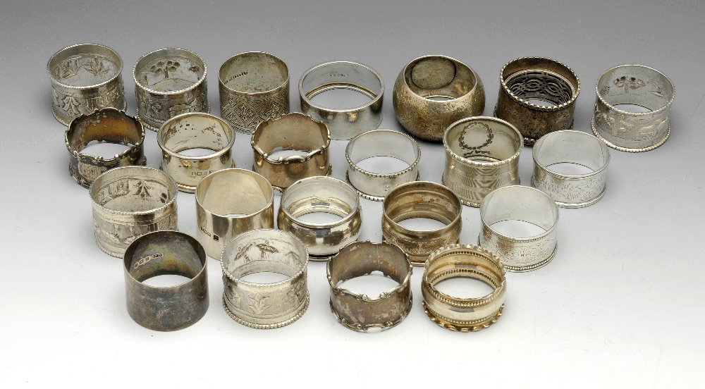 A selection of twenty three assorted napkin rings.: A selection of twenty three napkin rings of various shapes and styles, to include an Edwardian pair with scrolled rims and other engraved examples. Various hallmarks and makers, two napkin rings marke