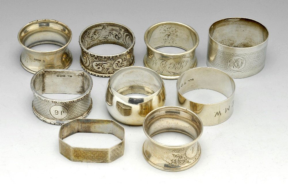 A selection of silver napkin rings. (9).: A pair of early twentieth century silver napkin rings of circular waisted form with foliate scroll cartouche, initialled, hallmarked London 1910. Together with a selection of seven single napkin rings