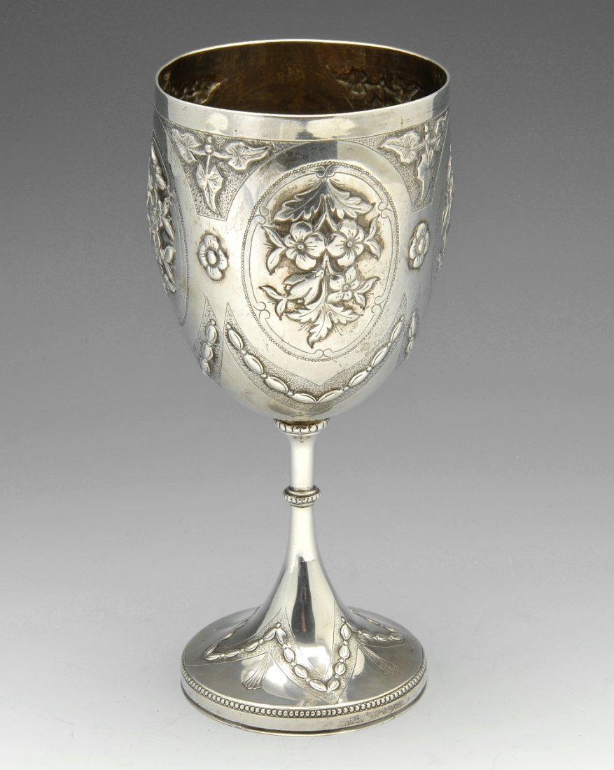 A 19th century goblet, likely Indian Colonial.: A nineteenth century goblet, decorated with foliate and garland motifs enclosing oval floral panels and a further panel with presentation engraving dated 1875, beaded and knopped stem leading to a spr