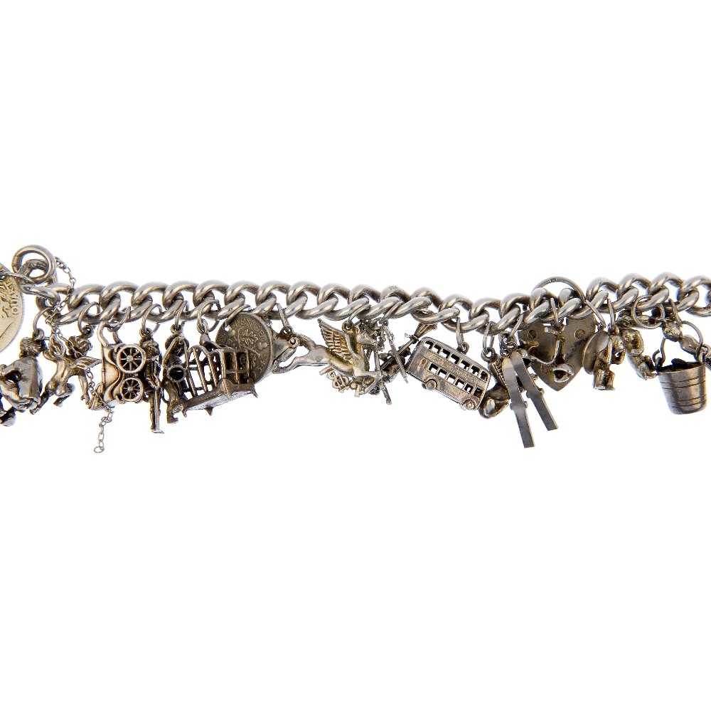 Two charm bracelets.: Two charm bracelets. The curb-link bracelets suspending nine and twenty-four charms, to include a double decker bus, an enamel Scottsman playing the bagpipes and a wishing well, both with heart padloc