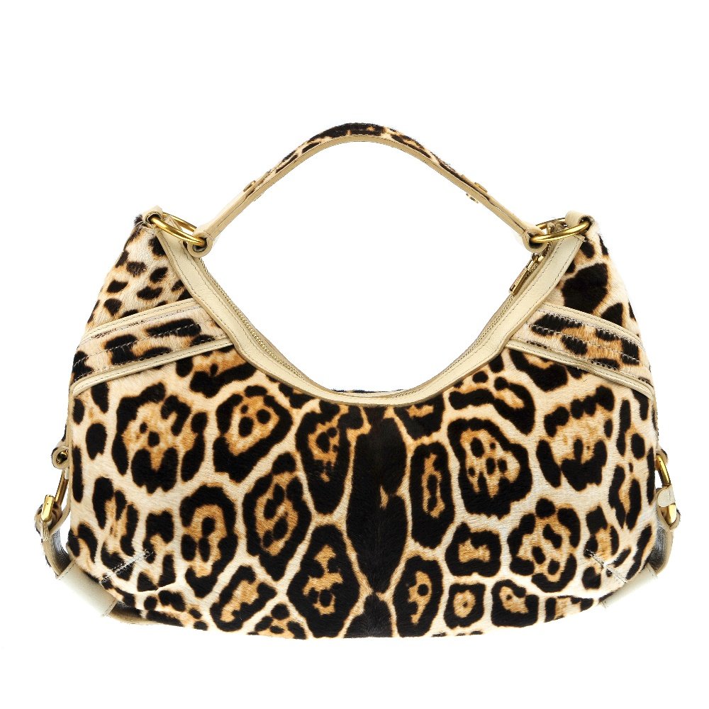YVES SAINT LAURENT - a fur and leather bag.: YVES SAINT LAURENT - a snow leopard print pony hair handbag. Designed with cream leather trim, short shoulder strap, zip closure, gold hardware and two interior pockets. Measures 8 by 28 by 39cms. Han