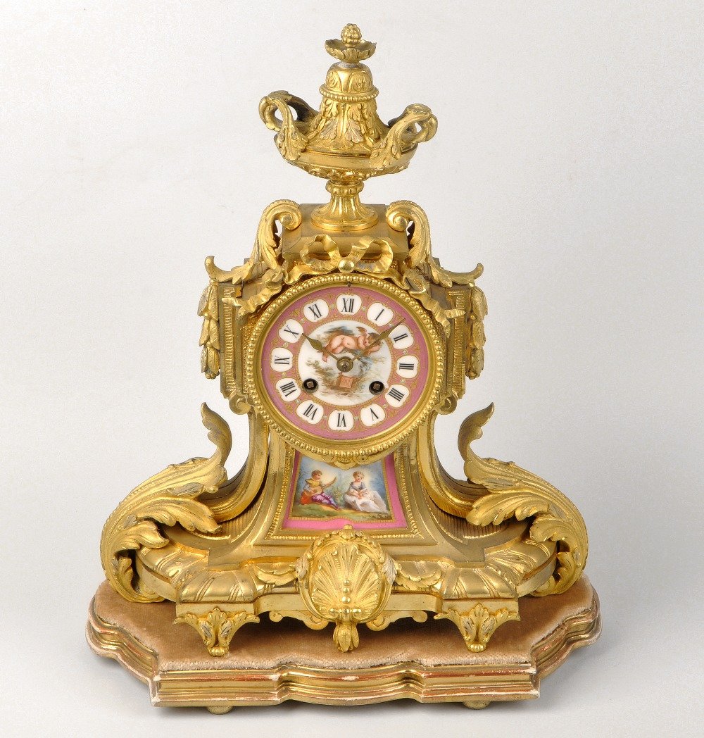 A mid 19th century French porcelain-mounted ormolu: A mid 19th century French porcelain-mounted ormolu mantel clock. Japy Freres, Paris The 3.5-inch circular dial with cellular Roman chapters reserved on a jewelled rose pink ground, framing a painted p