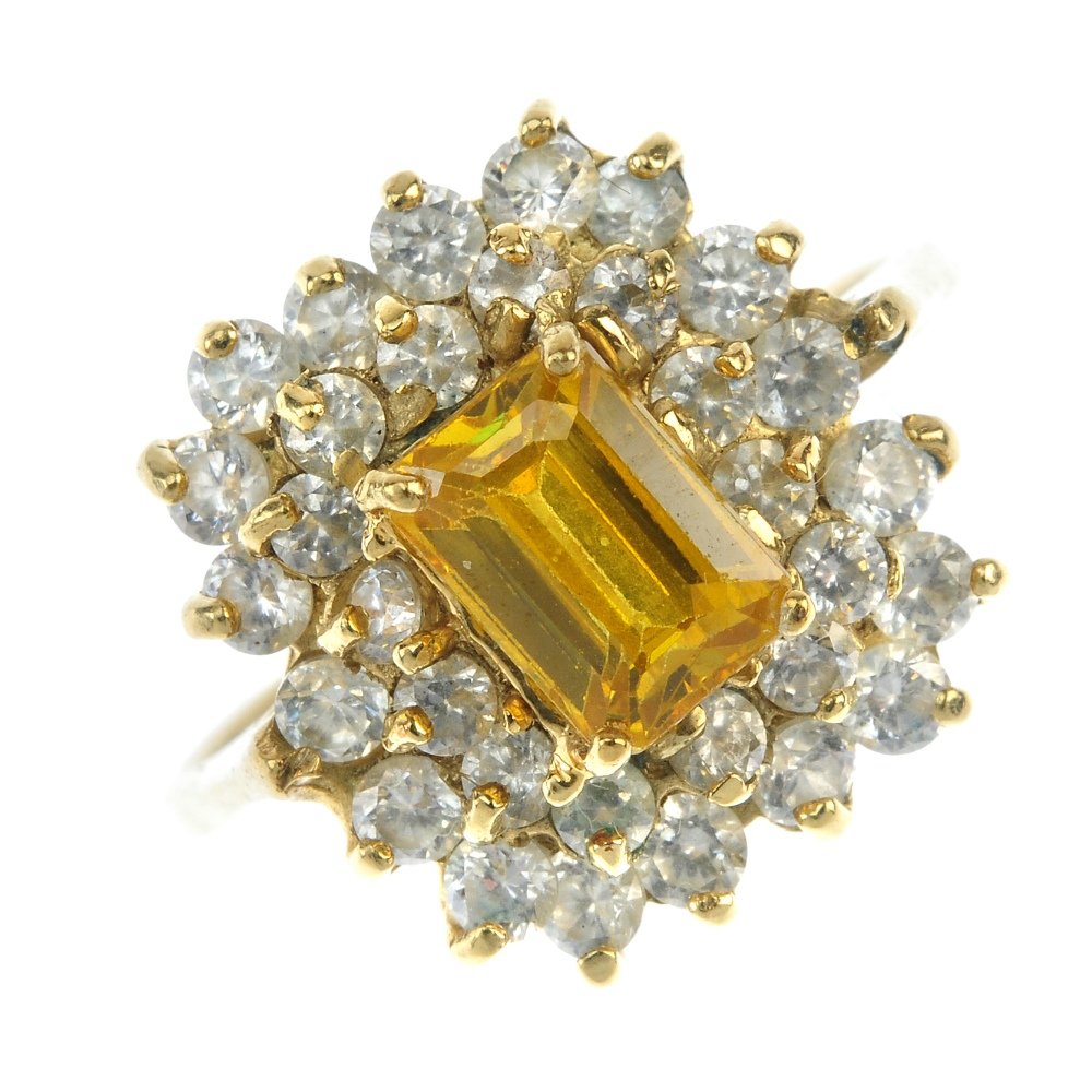 A paste cluster ring.: A paste cluster ring. The rectangular-shape yellow paste, within a circular-shape colourless paste surround. Weight 6.5gms.