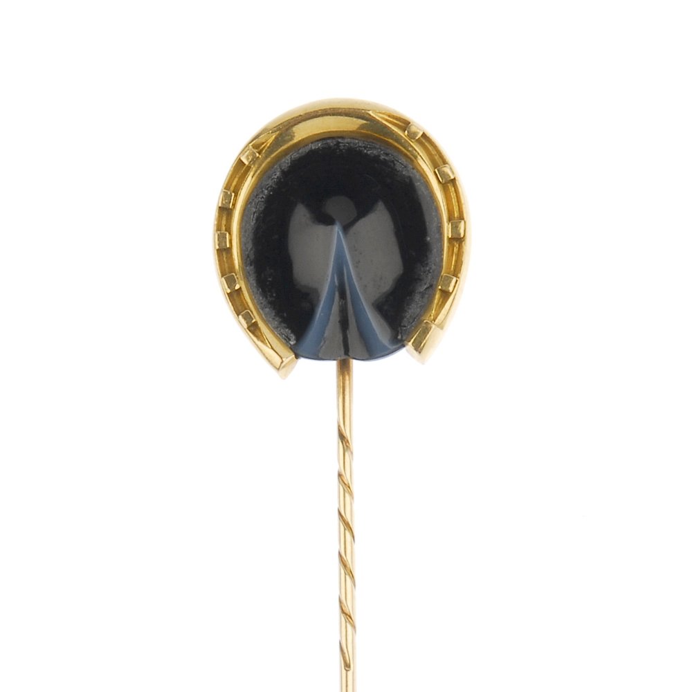A late 19th century 18ct gold agate horse's hoof: A late 19th century 18ct gold agate horse's hoof stickpin. Designed as a carved banded agate hoof, within a horseshoe surround. Length 8.4cms. Weight 6.2gms.
