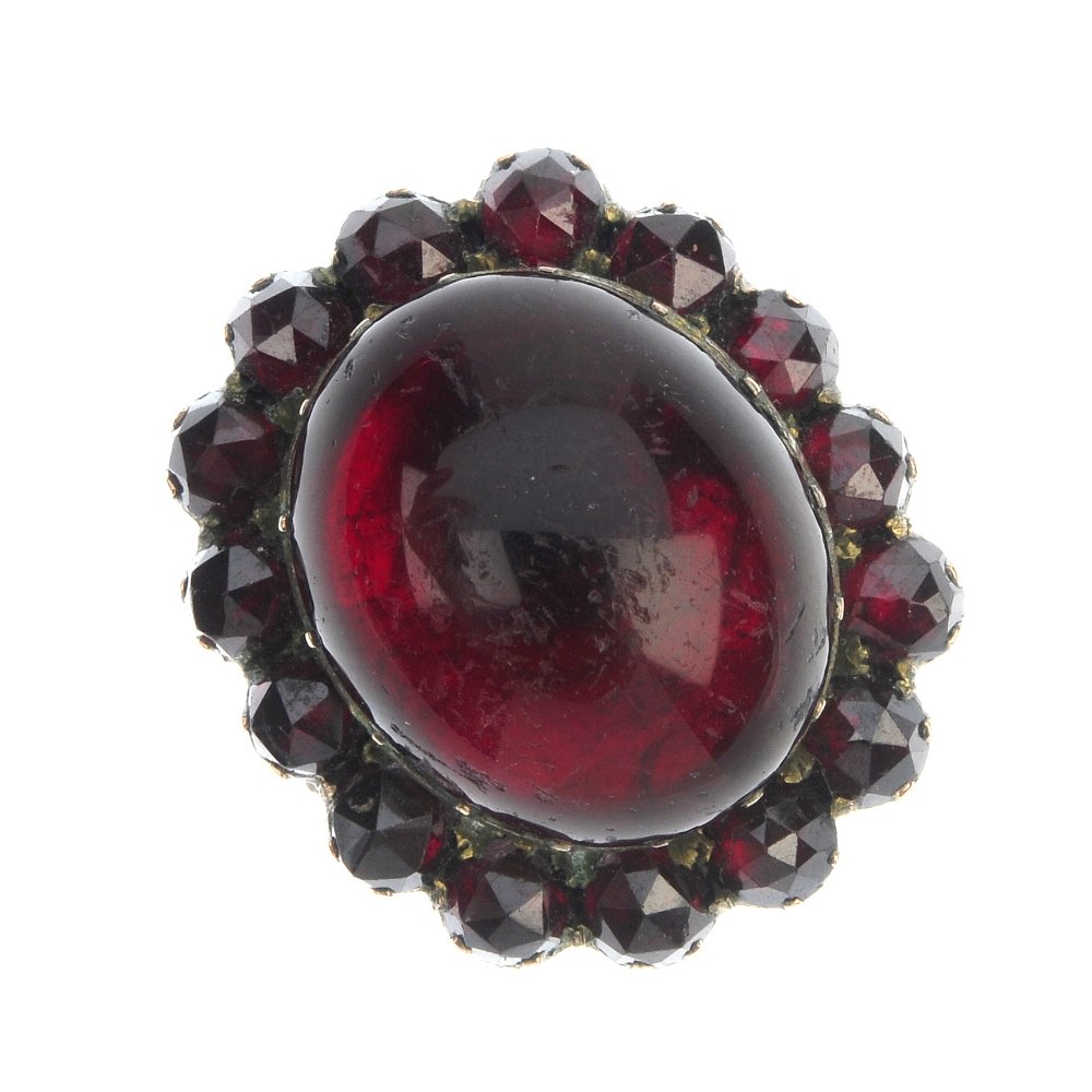 A late 19th century gold paste cluster ring.: A late 19th century gold paste cluster ring. The oval red paste cabochon, within a circular-shape red paste surround, to the bifurcated shoulders and plain band. Weight 6.7gms.
