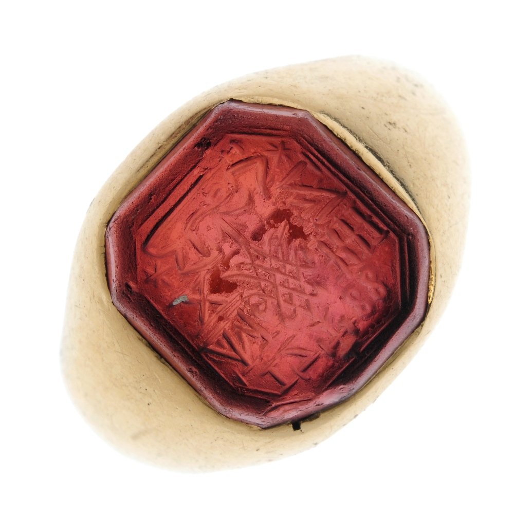 A garnet intaglio signet ring.: A garnet intaglio signet ring. The rectangular-shape garnet, engraved with various numbers and insignia, to the tapered shoulders and band with foreign script engraving to the inside of the band. Weig