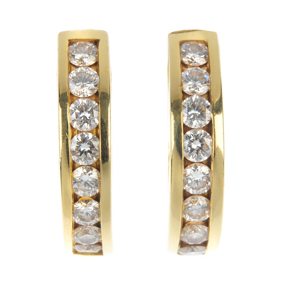 TIFFANY & CO. - a pair of diamond earrings.: TIFFANY & CO. - a pair of diamond earrings. Each designed as a brilliant-cut diamond curved line, within a channel-setting. Estimated total diamond weight 1.10cts, G-H colour, VS-SI clarity. Length 1.
