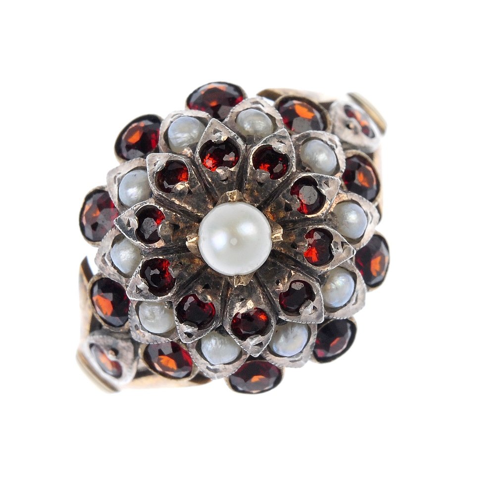A garnet and seed and split pearl cluster ring.: A garnet, seed and split pearl floral cluster ring. The seed pearl, within a circular-shape garnet and split pearl petal stepped surround, to the circular-shape garnet trifurcated sides. Weight 5.2gms