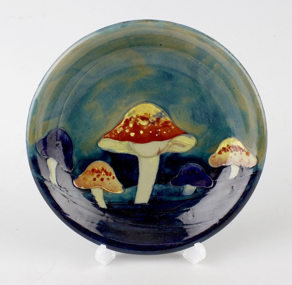 A William Moorcroft Claremont pattern pottery dish.: A William Moorcroft Claremont pattern pottery dish, circa 1918, having tube-lined decoration of toadstools on a sea-green ground shading to dark blue, blue initials and impressed marks, 8.5", (21.5cm)