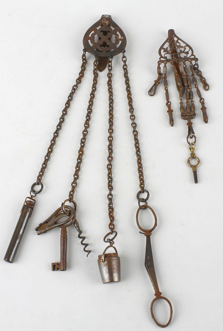 Two Victorian steel chatelaines.: Two Victorian steel chatelaines.The larger with rosette-centred bucklehook supporting four belcher-link chains to a bodkin case, button hook, corkscrew, key, pail-form thimble case, and folding scisso
